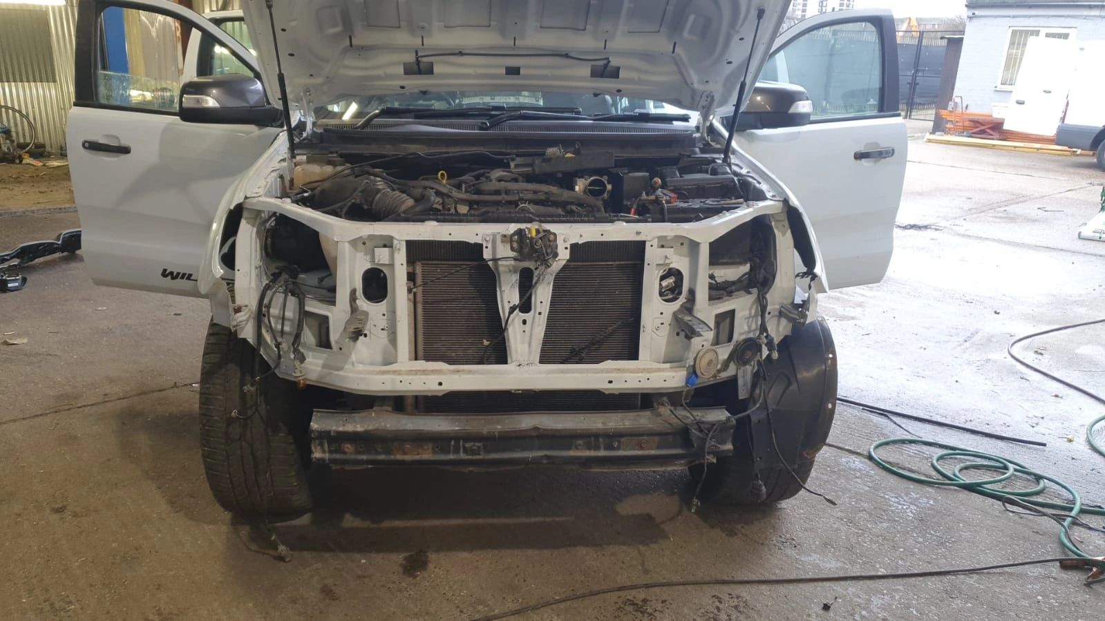 Pickup with front stripped, engine bay exposed for mechanical work