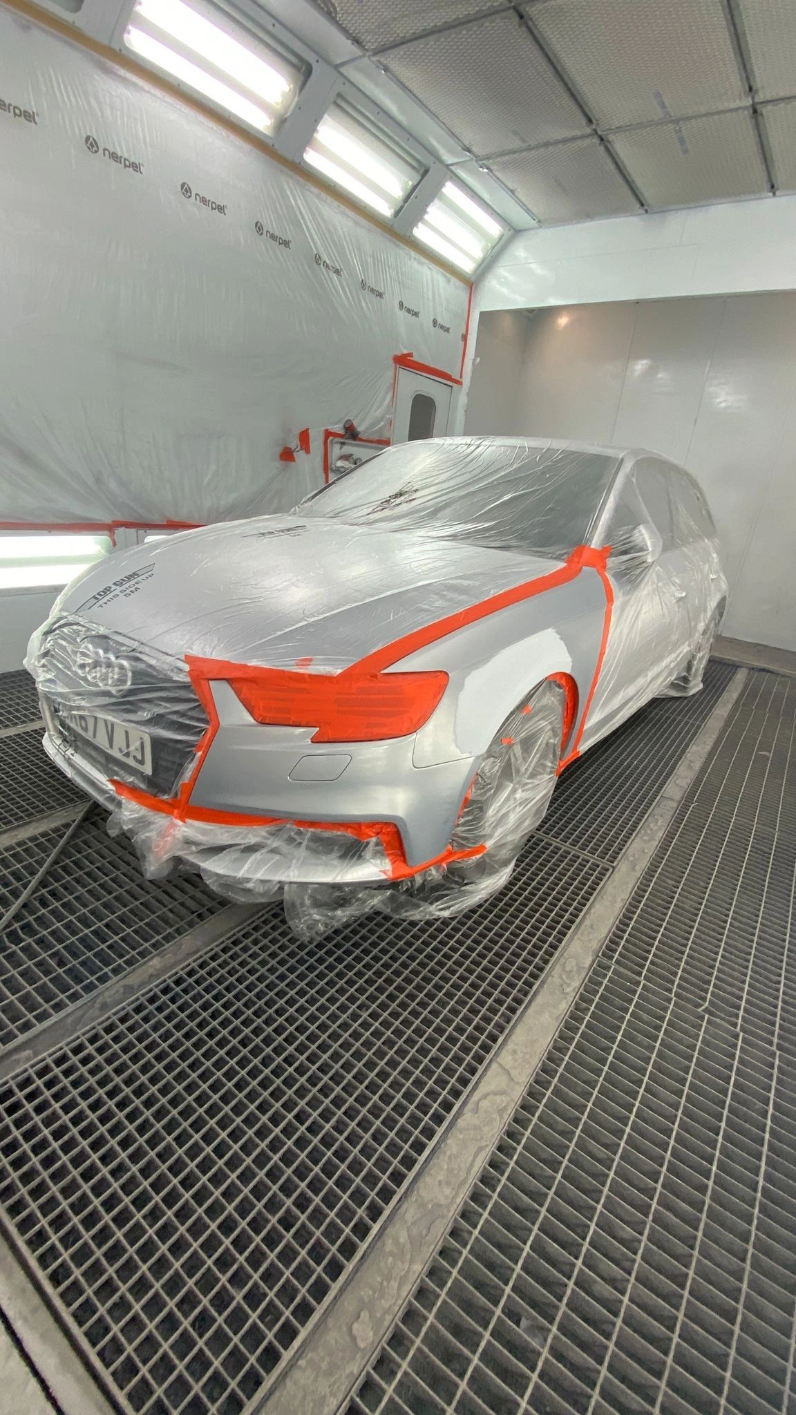 Silver Audi masked and prepped for paint in a spray booth