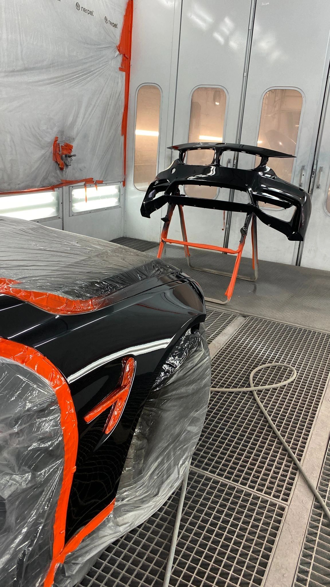 Car parts and wheels in a spray booth under workshop lighting