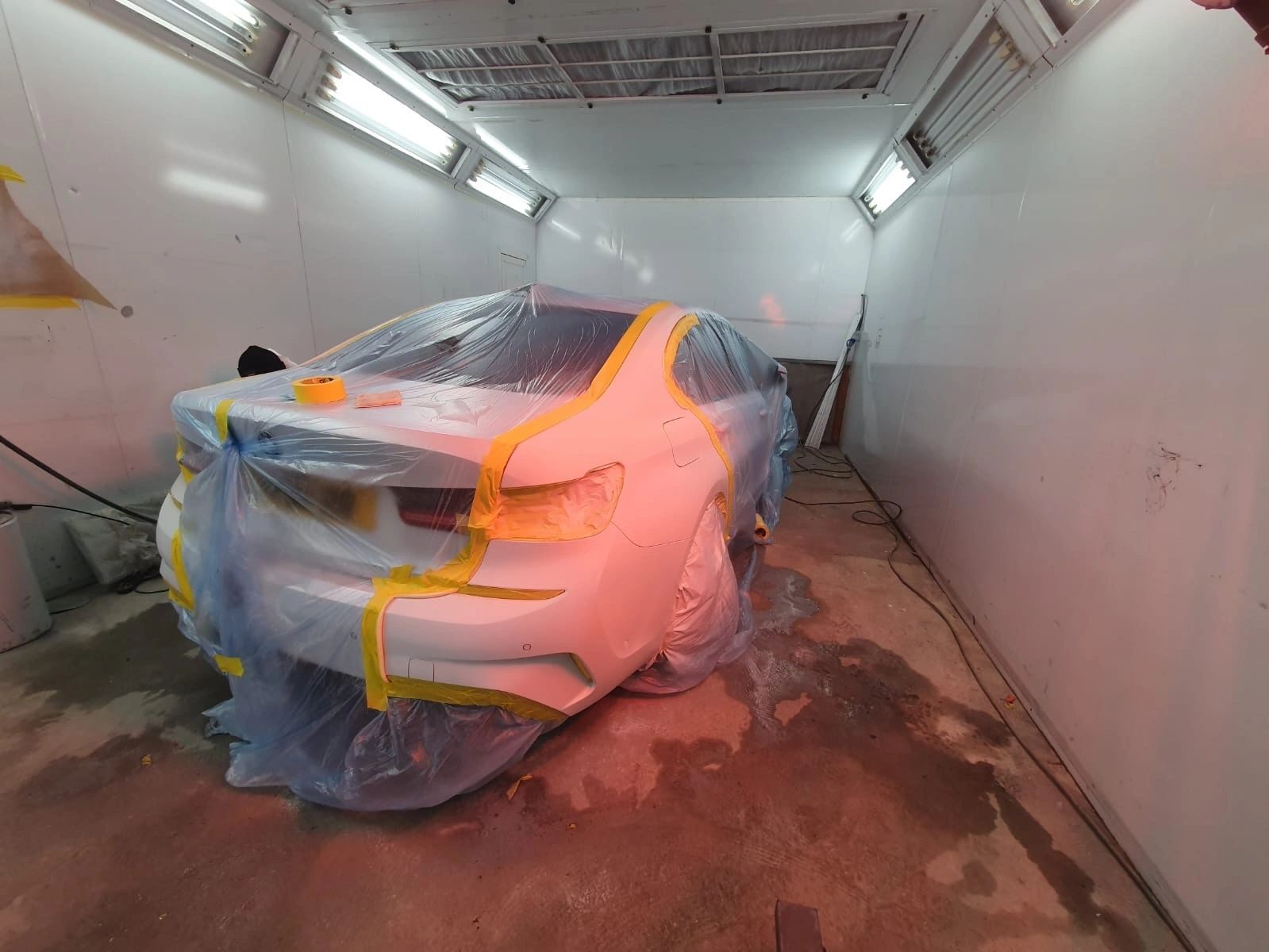 A car in grey primer inside a spray booth, masked up and ready for a full respray